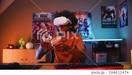 Teenage gamer in VR headset plays virtual online video game Teenage gamer in VR headset plays virtual online video game 104612474