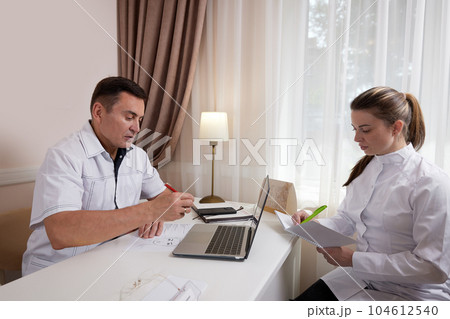 Two doctors man and woman talking, looking at computer screen 104612540