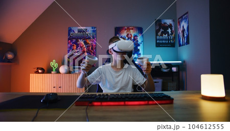 Young gamer in VR headset plays virtual online video game 104612555