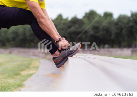 in urban park, a man in black leggings tie his sport shoes on bench, getting ready for exercise, 104613262