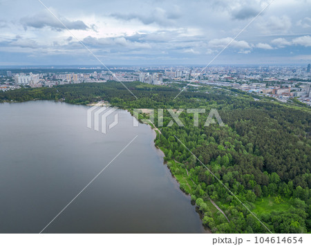 Big lake with green shores in bright sun light and city on horizon, aerial landscape. Recreation concept. Aerial view 104614654