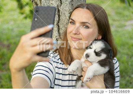 Woman in a t-shirt and jeans with a husky puppy takes a photo or selfie 104616609