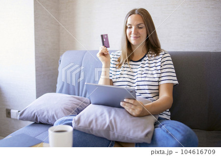 Woman excited about shopping online and holding her credit card 104616709