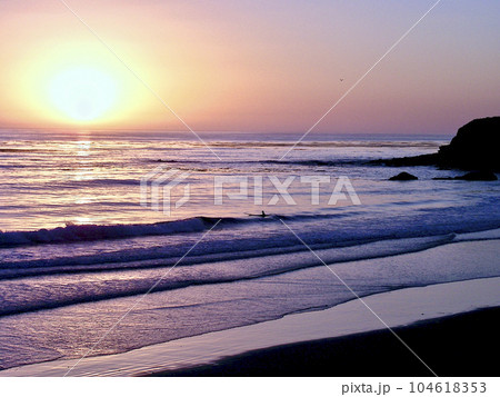 アメリカ　カリフォルニア　モントレー 夕日に照らされて波を待つサーファー 104618353