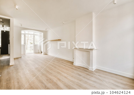 an empty living room with wood flooring and white walls, there is a fireplace in the center of the room 104624124