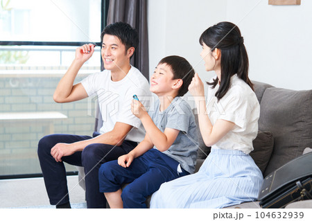ソファーに座りゲームを楽しむ親子　 104632939