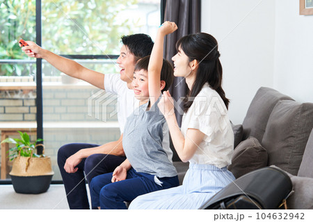 ソファーに座りゲームを楽しむ親子　 104632942