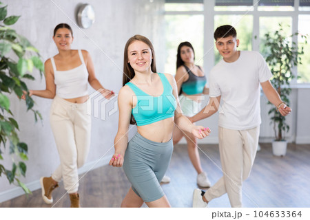 Girl teen perform choreographic exercise and teach energetic mobile social dance groove with friends Girl teen perform choreographic exercise and teach energetic mobile social dance groove with friends 104633364