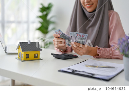 Young real estate agent counting and calculating her income and commision 104634021