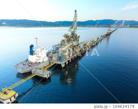夏の北海道北斗市函館湾でセメント工場のベルトコンベアー施設と貨物船の朝の風景を撮影 104634579