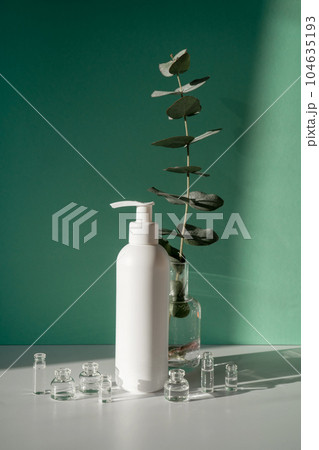 Eucalyptus and jars of cosmetics on a green background. 104635193