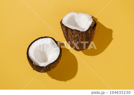 Two halves of coconut on a bright yellow background. Two halves of coconut on a bright yellow background. 104635230