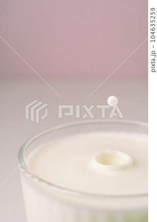 Milk drips into a transparent faceted glass. Milk drips into a transparent faceted glass. 104635259