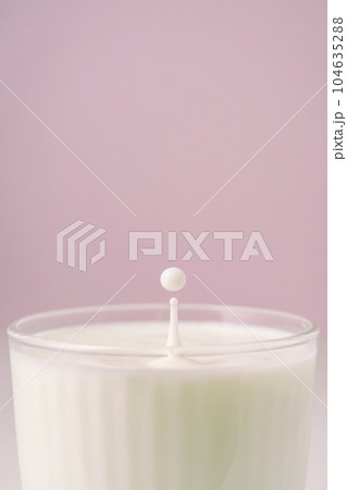 Milk drips into a transparent faceted glass. 104635288