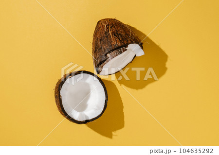 Two halves of coconut on a bright yellow background. 104635292