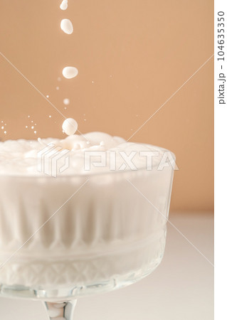 Milk pours into a beautiful crystal glass and splashes around. 104635350