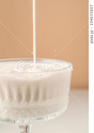Milk pours into a beautiful crystal glass and splashes around. 104635607
