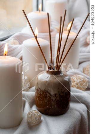 Aroma reed diffuser. Bottle container with wood stick diffusers Essential oils to scent your home fragnance concept autumn holidays at cozy home on the windowsill Hygge aesthetic atmosphere on knitted Aroma reed diffuser. Bottle container with wood stick diffusers Essential oils to scent your home fragnance concept autumn holidays at cozy home on the windowsill Hygge aesthetic atmosphere on knitted 104635953