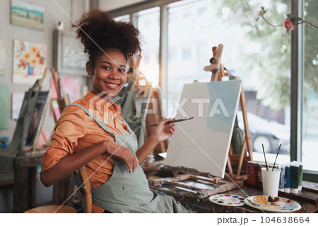 Beautiful american african artist woman painting in art studio at the university classroom Beautiful american african artist woman painting in art studio at the university classroom 104638664