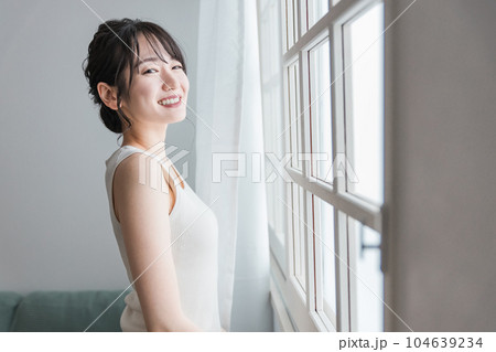 起きてカーテンを開けて朝日、日光を浴びる笑顔のアジア人女性 起きてカーテンを開けて朝日、日光を浴びる笑顔のアジア人女性 104639234