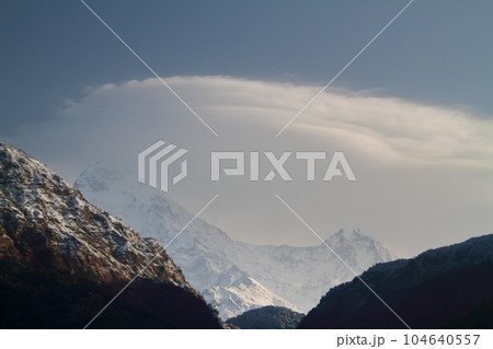 南アジアネパール　ヒマラヤトレッキングコースのウレリ村からアンナプルナサウスとヒウンチュリの頂と笠雲 104640557