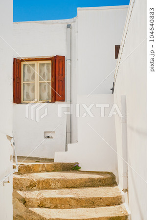 Greek street in a shopping center in Lindos, Rhodes island, Greek islands of the Dodecanese archipelago, Europe. Holidays and travel around the islands, vertical frame Greek street in a shopping center in Lindos, Rhodes island, Greek islands of the Dodecanese archipelago, Europe. Holidays and travel around the islands, vertical frame 104640883