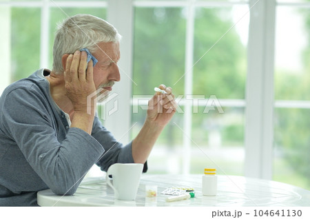Portrait of sad sick old man with thermometer Portrait of sad sick old man with thermometer 104641130