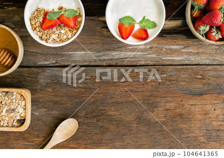 Strawberry yogurt in a wooden bowl with granola, mint and fresh strawberry on wooden background. Health food concept 104641365