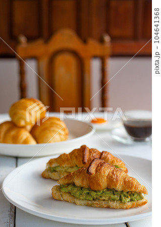 Croissant sandwich with egg,avocado on white dish and honey, coffee. breakfast and healthy food concept.. Croissant sandwich with egg,avocado on white dish and honey, coffee. breakfast and healthy food concept.. 104641368