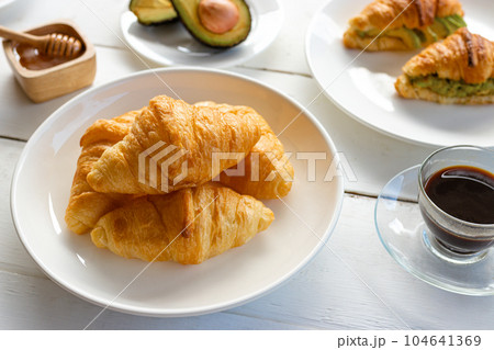 Croissant with egg,avocado on white dish and honey, coffee. breakfast and healthy food concept.. Croissant with egg,avocado on white dish and honey, coffee. breakfast and healthy food concept.. 104641369
