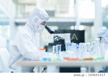 クリーンルームで顕微鏡を使って実験をする研究者 クリーンルームで顕微鏡を使って実験をする研究者 104641417