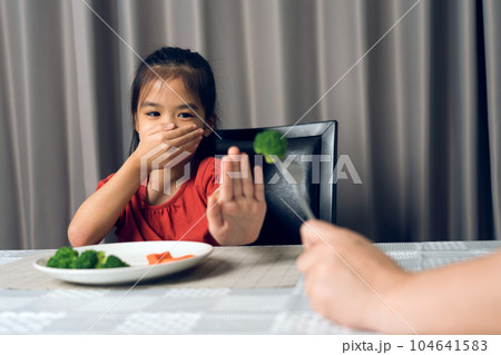 Little cute kid girl refusing to eat healthy vegetables. Children do not like to eat vegetables. 104641583