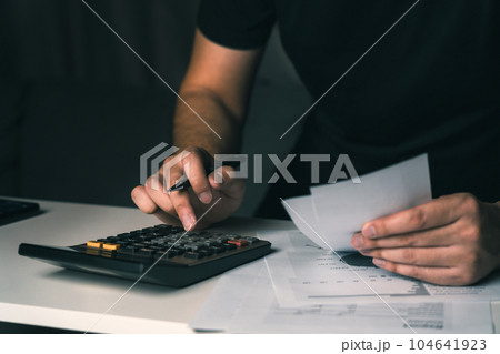 Asian man using calculator to calculate expenses while holding family bills at his home. 104641923