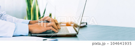 Doctor was sitting in the office working on a laptop computer. 104641935