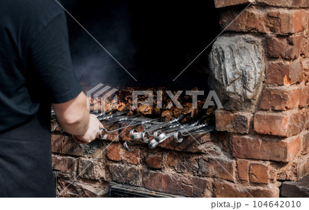 a man cooks kebab outdoor. 104642010