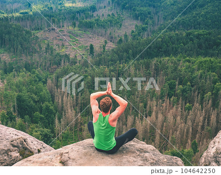 Man in yoga pose on rocky peak. Exercise yoga Man in yoga pose on rocky peak. Exercise yoga 104642250