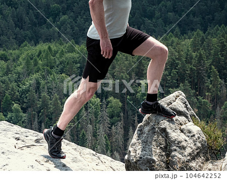 Long legs in hiking shoes on peak. Hiking in sandstone rocks 104642252