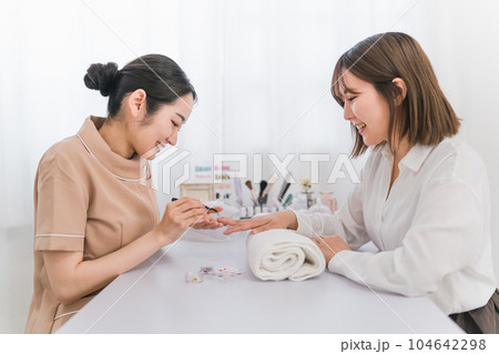 ネイルサロンでオプションのデザインを相談するネイリストとアジア人女性 104642298