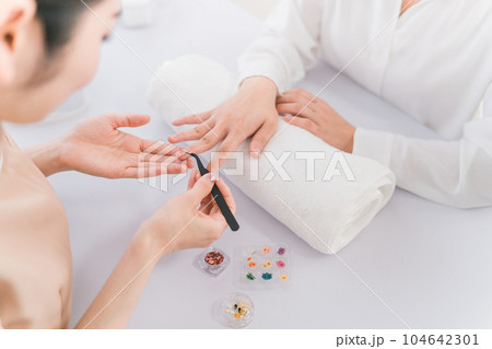 ネイルサロンでオプションのデザインを相談するネイリストとアジア人女性 104642301