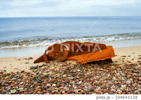 A rusty metal fragment of a ship's side thrown onto the seashore 104643138