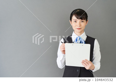 メモを書くベストにリボンタイの制服を着た受付業務、事務業務の女性 メモを書くベストにリボンタイの制服を着た受付業務、事務業務の女性 104643532