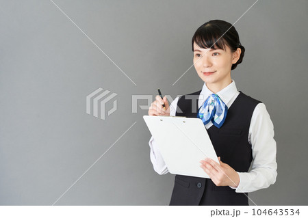 メモを書くベストにリボンタイの制服を着た受付業務、事務業務の女性 104643534