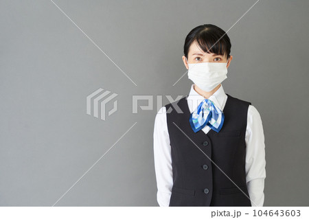 マスクをするベストにリボンタイの制服を着た受付業務、事務業務の女性 104643603