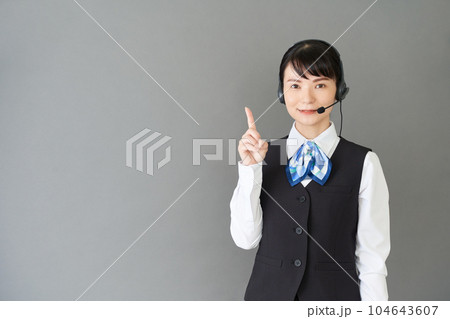 ヘッドセットをするベストにリボンタイの制服を着た受付業務、事務業務の女性 ヘッドセットをするベストにリボンタイの制服を着た受付業務、事務業務の女性 104643607