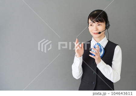 ヘッドセットをするベストにリボンタイの制服を着た受付業務、事務業務の女性 ヘッドセットをするベストにリボンタイの制服を着た受付業務、事務業務の女性 104643611