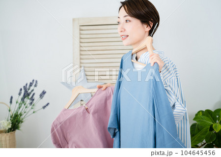 鏡の前で服選びをしている若い女性　ファッションイメージ 104645456