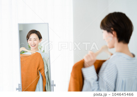 鏡の前で服選びをしている若い女性 ファッションイメージ 鏡の前で服選びをしている若い女性 ファッションイメージ 104645466