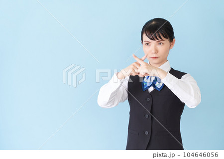 腕でバツ印を作るベストにリボンタイの制服を着た、受付業務、事務業務の女性 腕でバツ印を作るベストにリボンタイの制服を着た、受付業務、事務業務の女性 104646056