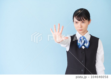 手を出して制止するベストにリボンタイの制服を着た、受付業務、事務業務の女性 104646058