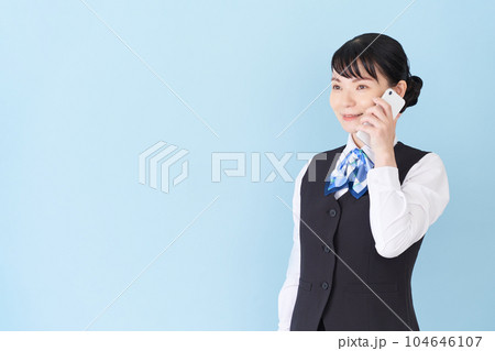 スマートフォンで電話をするベストにリボンタイの制服を着た、受付業務、事務業務の女性 スマートフォンで電話をするベストにリボンタイの制服を着た、受付業務、事務業務の女性 104646107